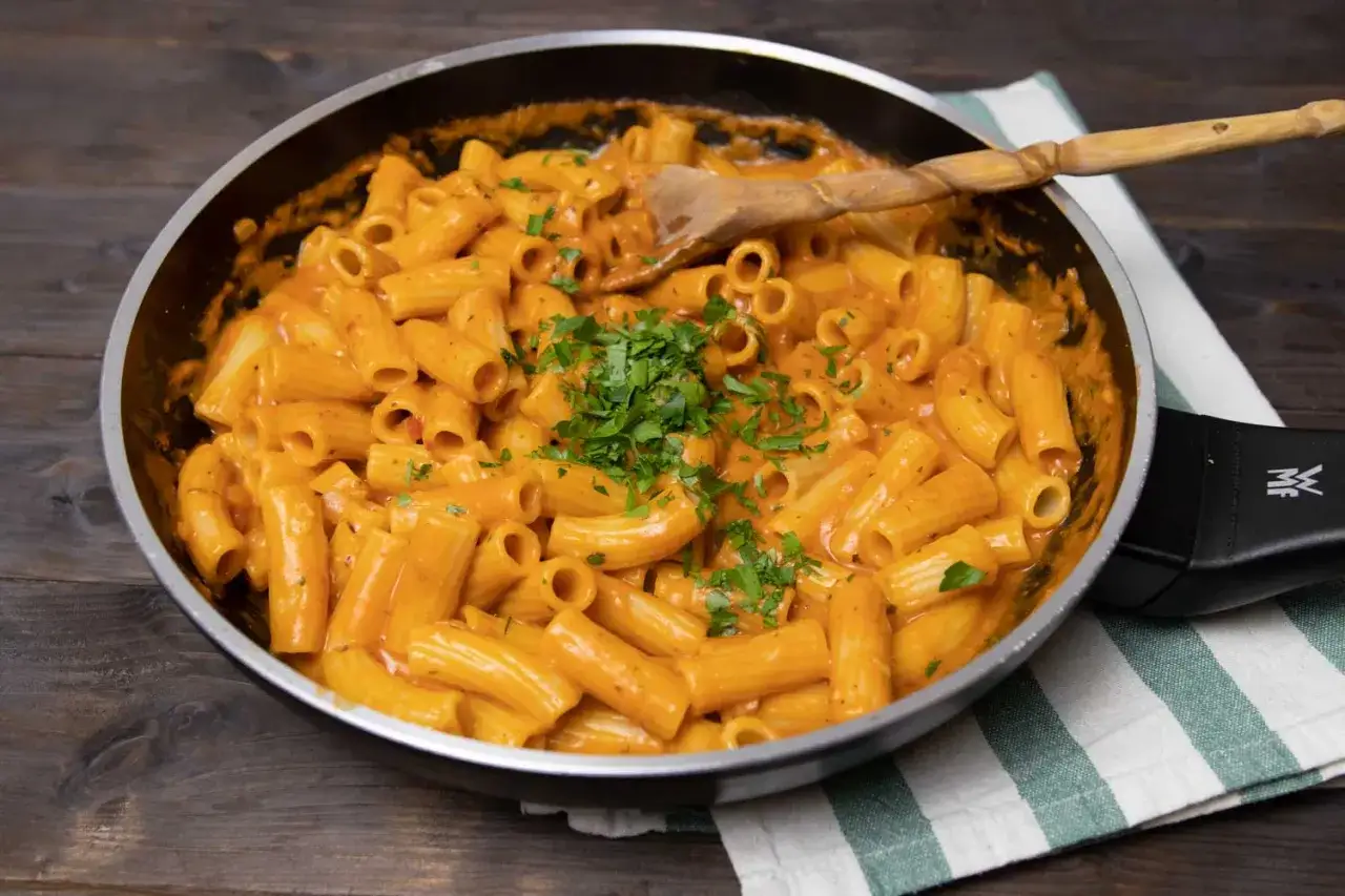 Eine Pfanne voller Rigatoni in cremiger Tomaten-Sahne-Sauce, garniert mit frischer Petersilie. Ein Genuss!