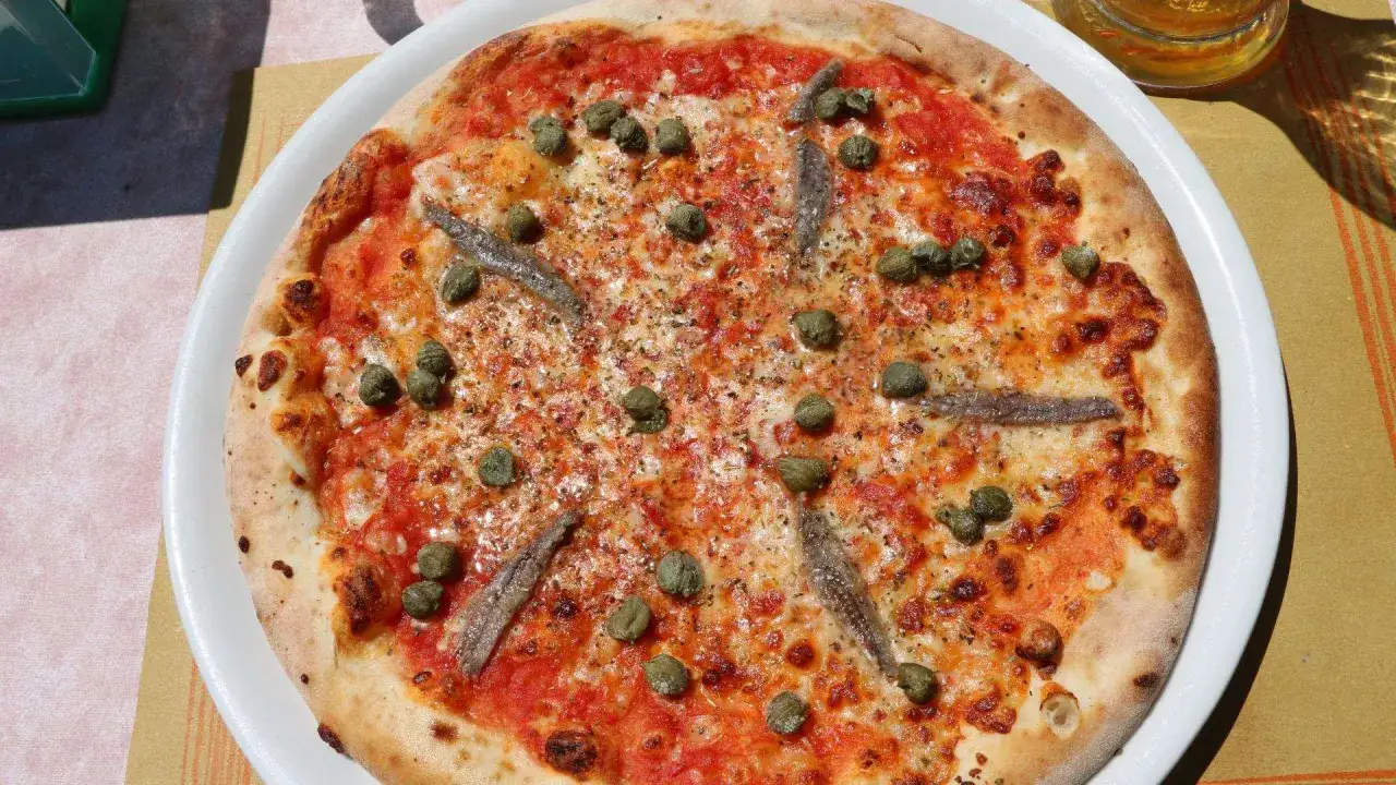 Pizza Romana mit Sardellen und Kapern. Was ist drauf? Tomatensauce, Käse, grüne Kapern und kleine Sardellenfilets.