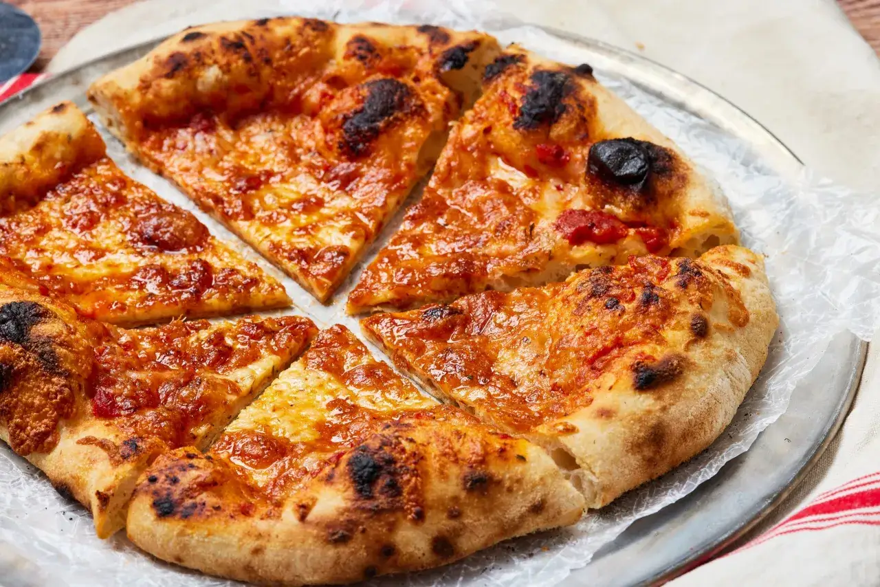 Eine k&ouml;stliche Pizza mit geschmolzenem K&auml;se und leicht verbranntem Rand, zubereitet mit Pizzateig mit Trockenhefe.