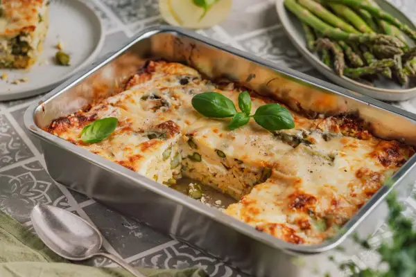 Herzhafte Spargel Lasagne mit geschmolzenem Käse, garniert mit frischem Basilikum. Ein Genuss für jeden Gaumen.