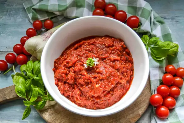 Frische tomaten pizza sauce, mit Basilikum und Knoblauch, umgeben von reifen Kirschtomaten.
