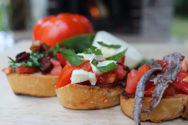 Drei italienische Bruschetta mit Tomaten, Mozzarella und Sardellen auf geröstetem Brot.