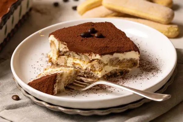 Ein Stück Tiramisu, perfekt für Ihr nächstes tiramisu rezept. Mit Löffelbiskuit, Creme und Kakao bestäubt.