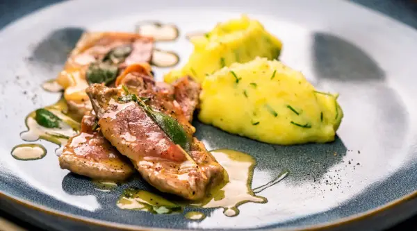 Saltimbocca alla Romana: zarte Kalbsschnitzel mit Salbei und Schinken in einer köstlichen Sauce, serviert mit cremigem Kartoffelpüree.