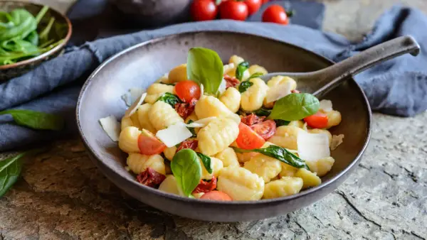 Ein köstlicher Gnocchi Salat mit Kirschtomaten, getrockneten Tomaten, frischem Basilikum und Parmesan.