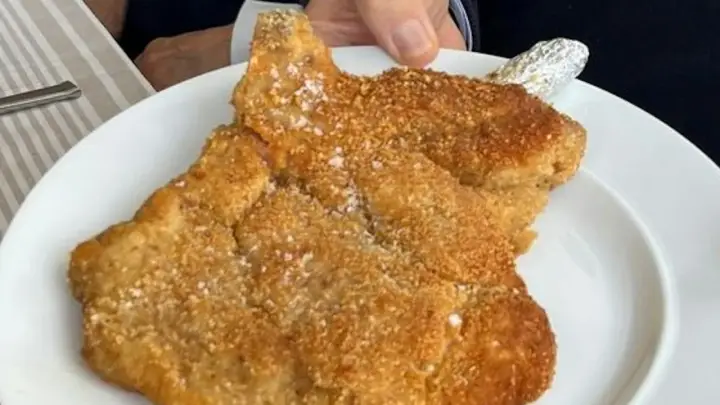 Ein knuspriges Piccata Milanese auf einem weißen Teller, bereit zum Genuss.