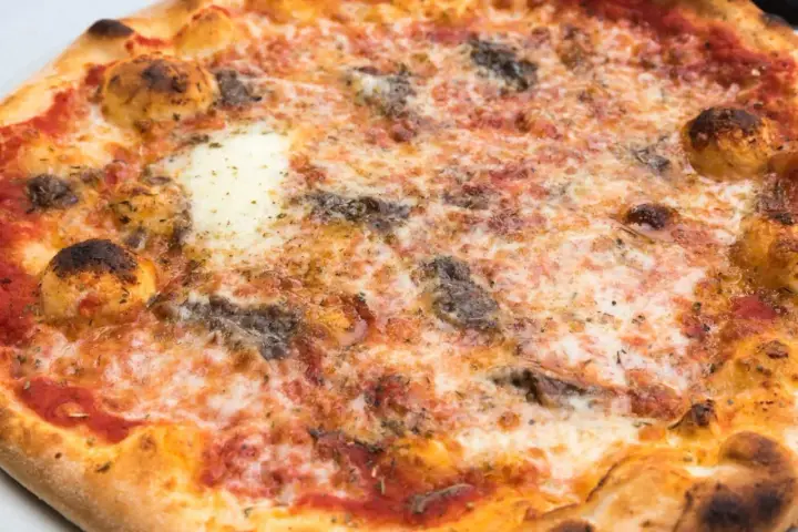 Eine knusprige Pizza Romana mit geschmolzenem Käse, Tomatensauce und dunklen, würzigen Belägen. Was ist drauf?