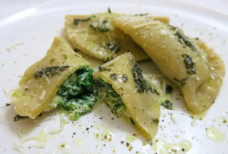 Mezzelune spinaci, gefüllt mit cremigem Spinat und Ricotta, beträufelt mit Olivenöl und bestreut mit Parmesan.